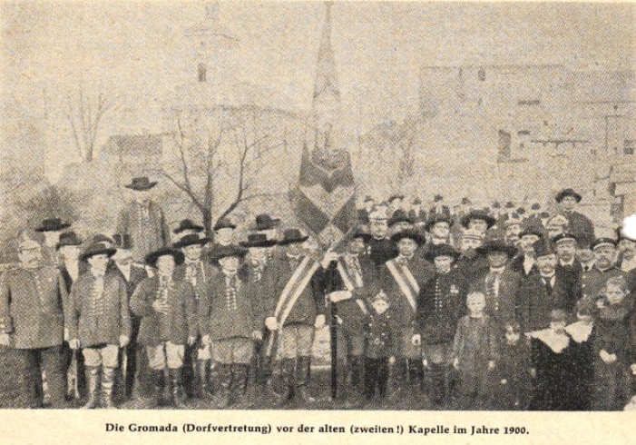 Członkowie Gromady Rozbarskiej w strojach ludowych stojący ze sztandarem przed kaplicą w 1900 r.