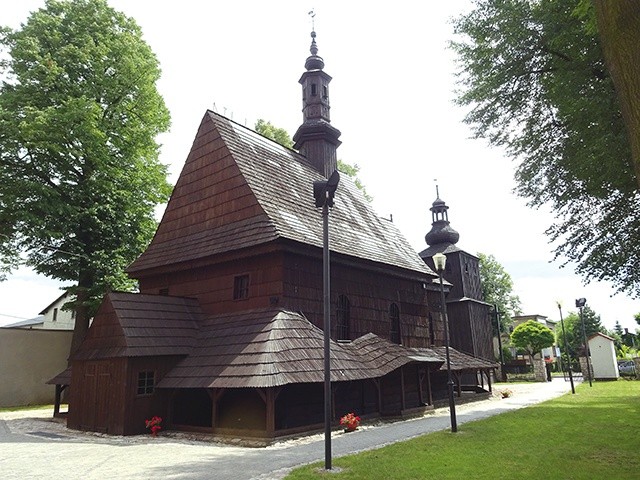Współczesne zdjęcie drewnianego kościoła z 1666 roku o konstrukcji zrębowej, otoczonego sobotami. W tle po prawej stronie widać wieżę dzwonnicy.