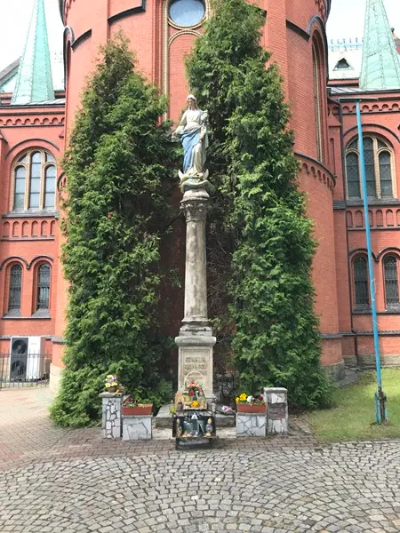 Widok ogólny na figurę Matki Boskiej wraz z pełną kolumną, cokołem i otoczeniem przed kościołem w Szombierkach